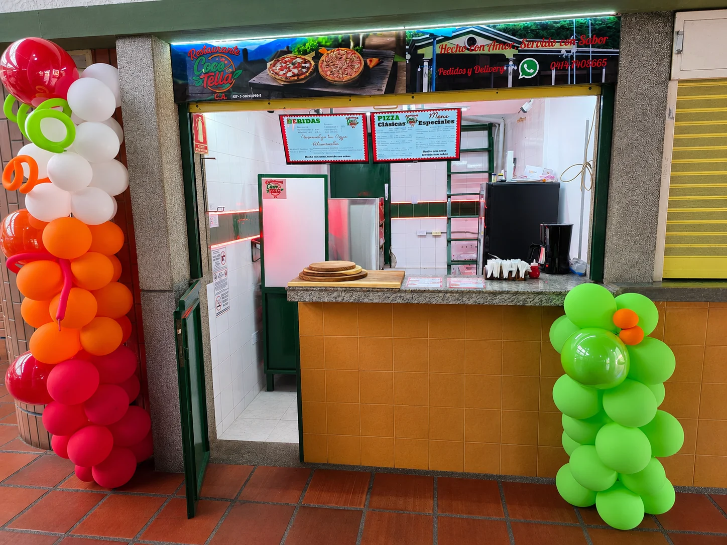 Fachada y mostrador de Restaurante Coco Tella decorado con globos